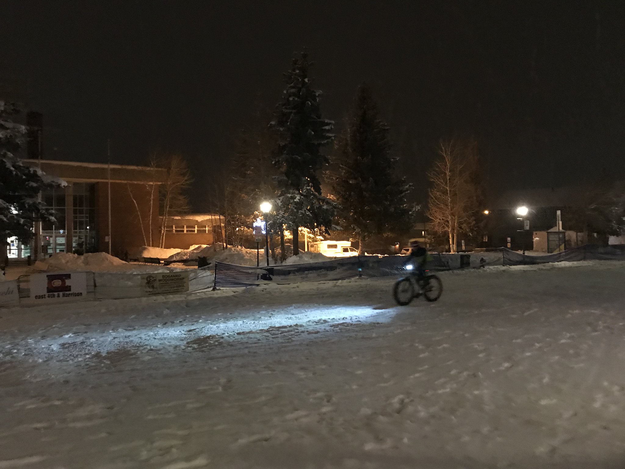 Someone riding a bicycle in the evening on a snowy street